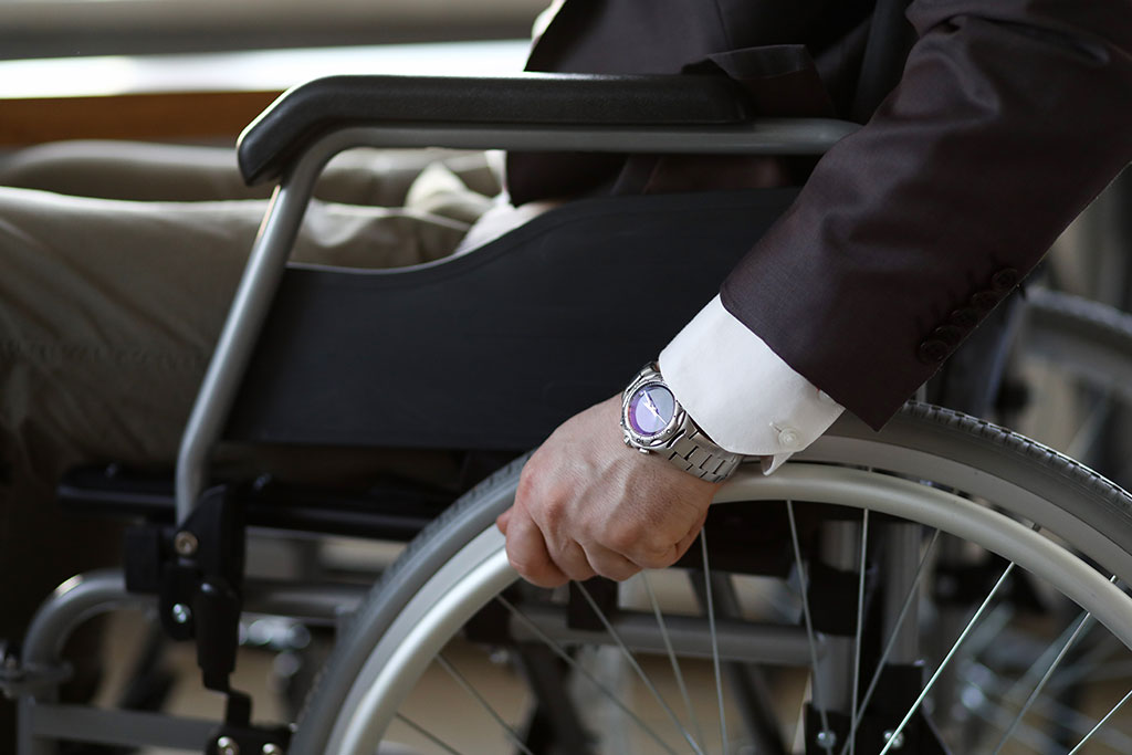 Disability businessman with wheelchair against business office background. Adaptation of people with disabilities in society concept