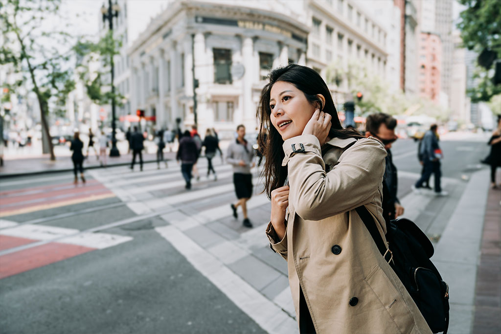 female asian tourist with curious face smiling standing on sidewalk